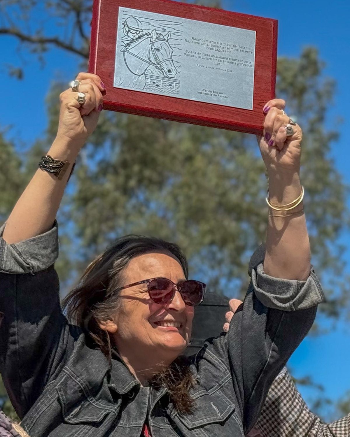Alejandra Pérez Álvarez levanta la placa el día de la inauguración del mural Irineo Leguisamo