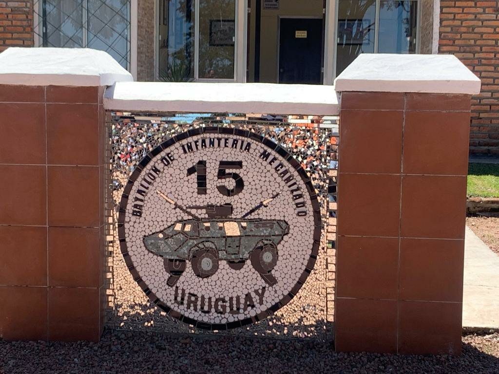 Mosaico de la heráldica del batallón en el acceso al predio: escudo circular "Batallón de Infantería Mecanizado 15 - Uruguay" con un vehículo blindado, entre dos pilares de ladrillo