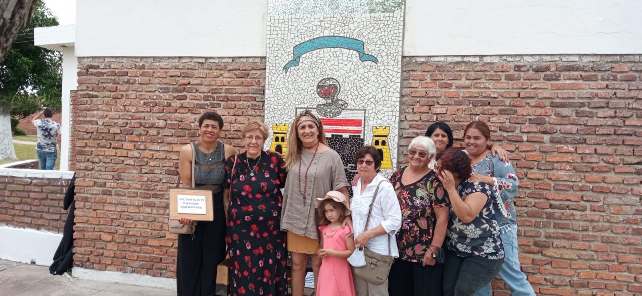 Integrantes del grupo y una niña posan frente al escudo del Batallón de Ingenieros, con la placa de agradecimiento en las manos.