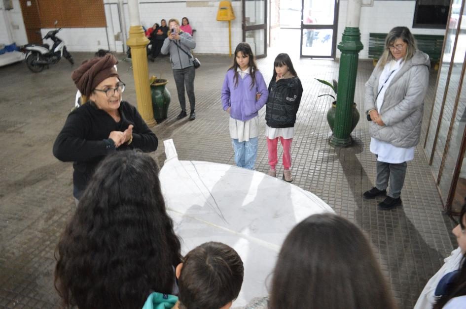 Alejandra Pérez (con turbante) explicando la obra a un grupo de escolares alrededor de la base de la pluma
