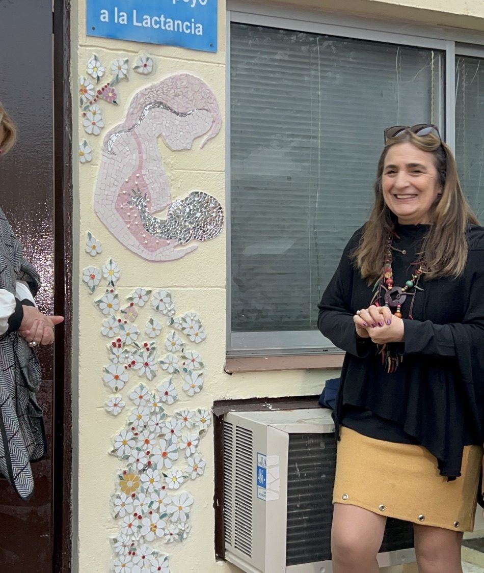 Detalle del mosaico de espejos y cerámica de la sala de lactancia: una madre con su bebé y flores.