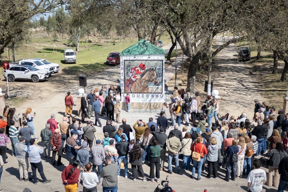 Vista elevada de la inauguración del mural Irineo Leguisamo: el público rodea el mural del caballo y el jockey en el acceso al Hipódromo.