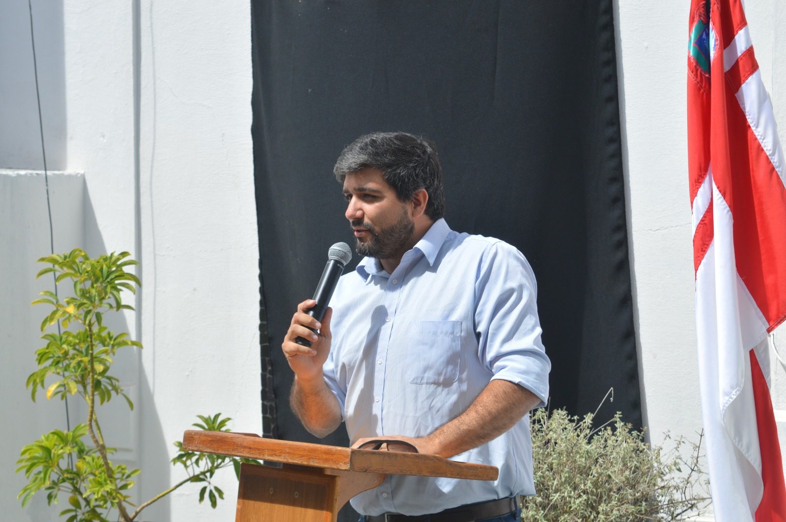 Autoridad de la Intendencia (varón, barba, camisa celeste) hablando al micrófono en el atril; posiblemente el secretario general Dr. Marcos Pérez o el director de Obras Arq. Facundo Urban