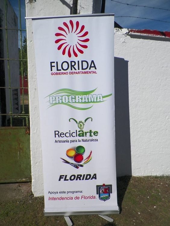 Cartel/banner institucional del programa "ReciclArte — Artesanía para la Naturaleza" de la Intendencia de Florida, fotografiado junto al lugar de la intervención